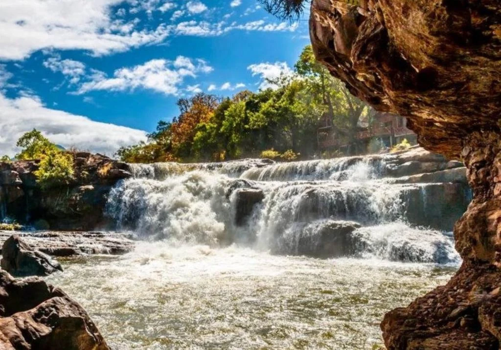 Tad Lo Waterfall flowing through the village landscape